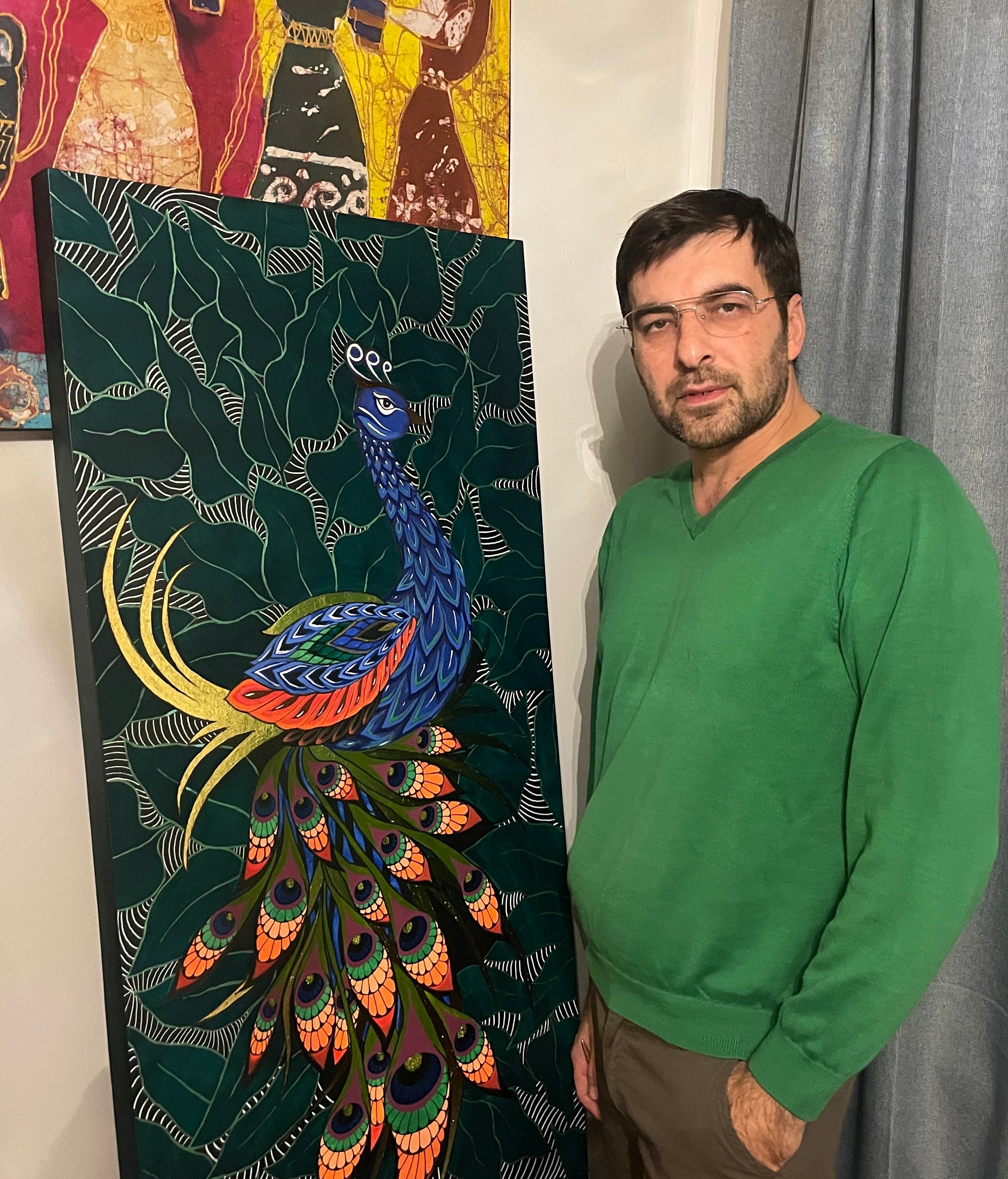 Azad Rustamov in the studio, beside one of his ornamental peacock paintings